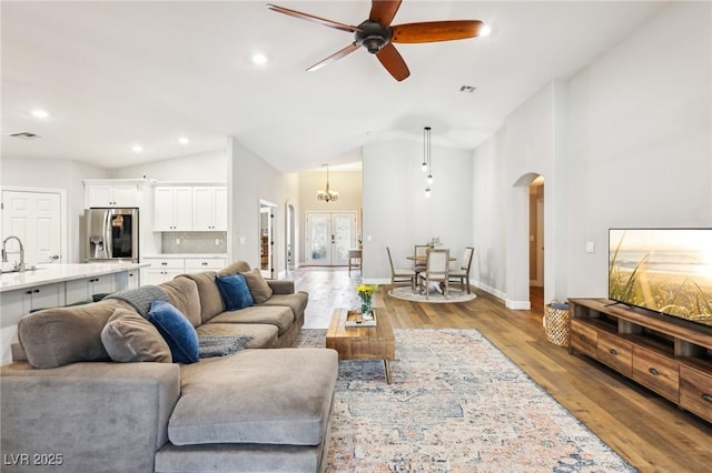 living area with arched walkways, vaulted ceiling, ceiling fan, recessed lighting, and wood finished floors