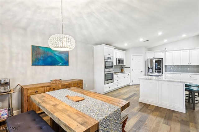 dining space featuring wood finished floors, lofted ceiling, recessed lighting, and a chandelier