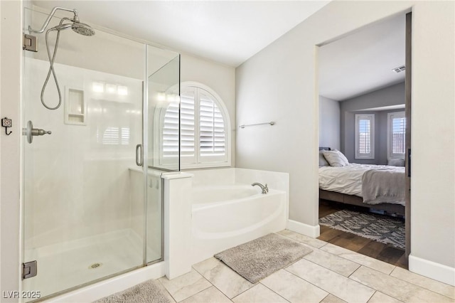 bathroom featuring ensuite bath, a garden tub, a stall shower, tile patterned floors, and vaulted ceiling