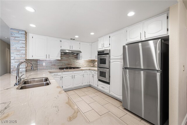 5449 Desert Spring Rd, Las Vegas, NV 89149 - kitchen with appliances with stainless steel finishes, a sink, under cabinet range hood, tasteful backsplash, and white cabinetry