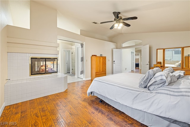 5449 Desert Spring Rd, Las Vegas, NV 89149 - bedroom with vaulted ceiling, hardwood / wood-style floors, a tile fireplace, ceiling fan, and baseboards