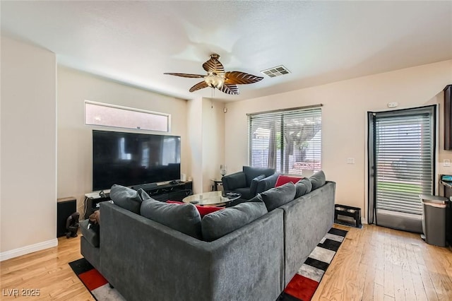 living area with light wood-style floors, a ceiling fan, and baseboards