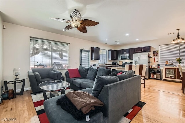 living room with ceiling fan, light wood-style floors, and recessed lighting