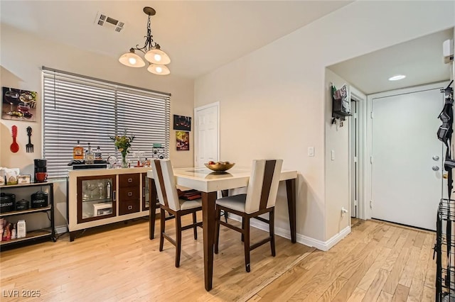 dining room featuring light wood finished floors, a chandelier, and baseboards