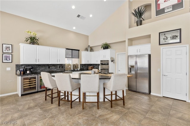 kitchen with stainless steel refrigerator with ice dispenser, high vaulted ceiling, wine cooler, tasteful backsplash, and white cabinets
