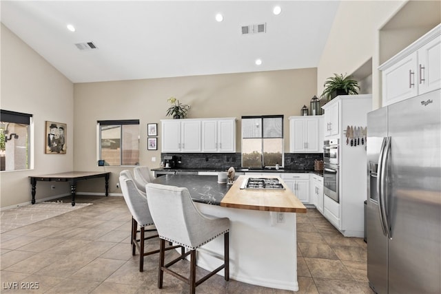 kitchen with stainless steel appliances, backsplash, a kitchen island, a sink, and a kitchen bar