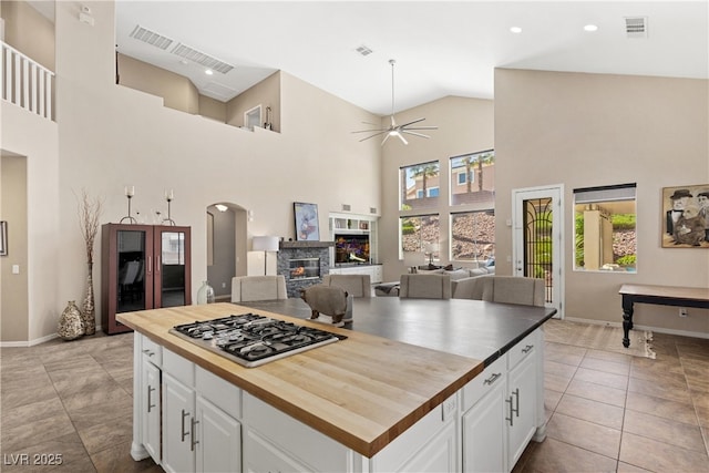 kitchen featuring stainless steel gas stovetop, butcher block counters, plenty of natural light, high vaulted ceiling, and white cabinetry