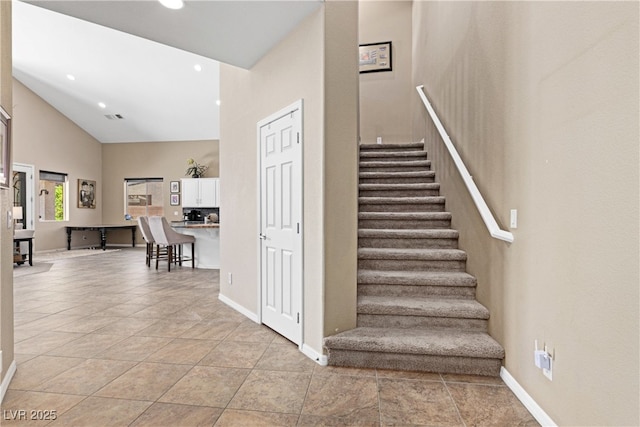 staircase with tile patterned floors, high vaulted ceiling, recessed lighting, and baseboards