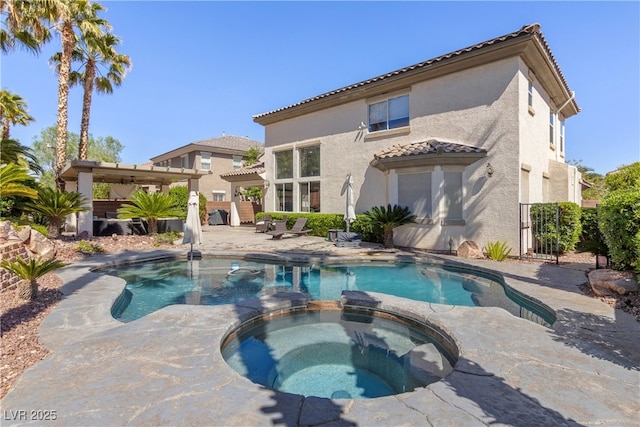 rear view of property featuring a tiled roof, stucco siding, a pool with connected hot tub, a patio, and fence