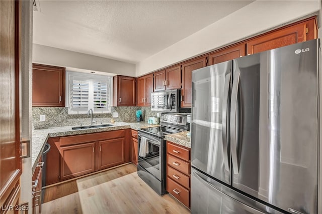 2725 S Nellis Blvd Unit 2052, Las Vegas, NV 89121 - kitchen featuring appliances with stainless steel finishes, a sink, light wood-type flooring, brown cabinets, and decorative backsplash