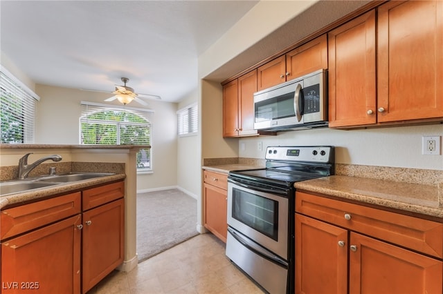 4400 S Jones Blvd Unit 2033, Las Vegas, NV 89103 - kitchen featuring appliances with stainless steel finishes, a sink, a ceiling fan, brown cabinets, and light colored carpet