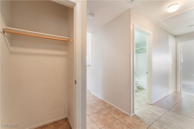 hallway featuring light tile patterned flooring and baseboards