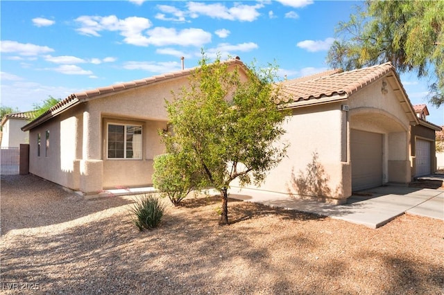 view of front facade with stucco siding, a tiled roof, driveway, and an attached garage