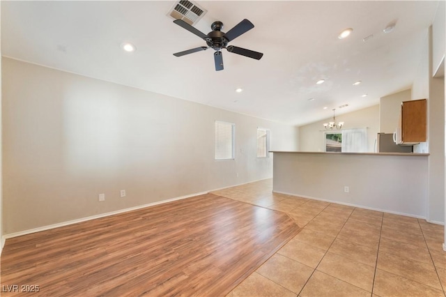 empty room featuring healthy amount of natural light, a chandelier, vaulted ceiling, a ceiling fan, and recessed lighting