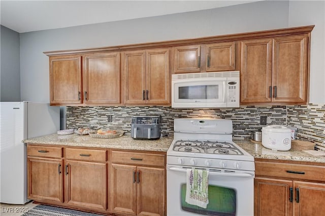 8250 Lincoln Valley St, Las Vegas, NV 89123 - kitchen with white appliances, decorative backsplash, brown cabinetry, and light stone counters
