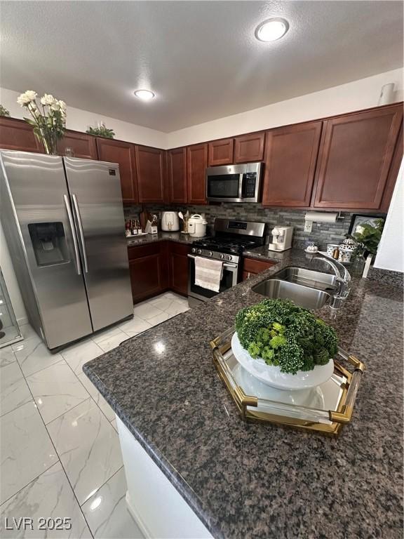 369 Stone Fly Rd, North Las Vegas, NV 89032 - kitchen with stainless steel appliances, a sink, dark stone countertops, backsplash, and a peninsula