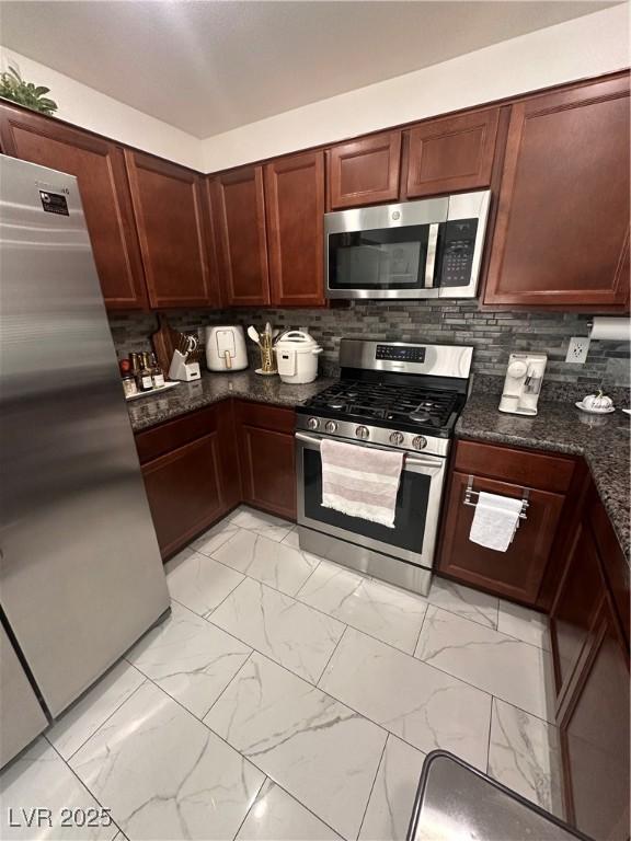 369 Stone Fly Rd, North Las Vegas, NV 89032 - kitchen with appliances with stainless steel finishes, light marble finish floors, backsplash, and dark stone counters