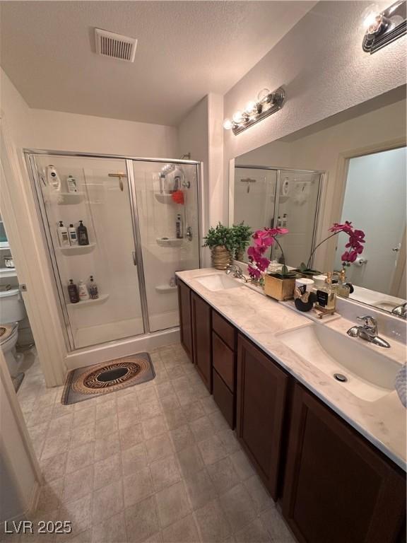 369 Stone Fly Rd, North Las Vegas, NV 89032 - bathroom with a stall shower, toilet, double vanity, and a textured ceiling