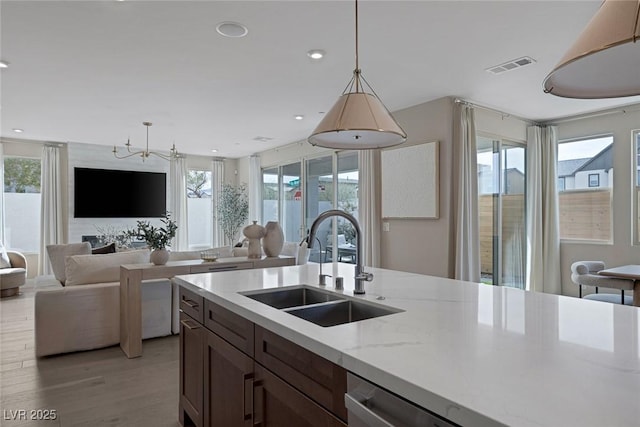 kitchen with a sink, open floor plan, decorative light fixtures, light wood-style flooring, and recessed lighting