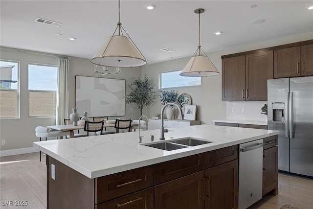 kitchen featuring stainless steel appliances, a sink, an island with sink, light wood finished floors, and recessed lighting