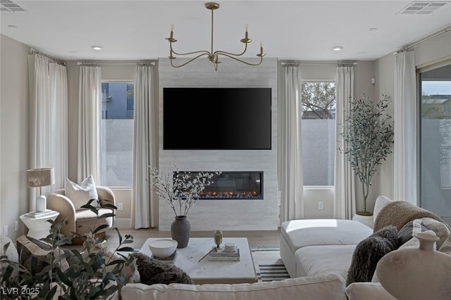living area with wood finished floors, a chandelier, recessed lighting, and a large fireplace