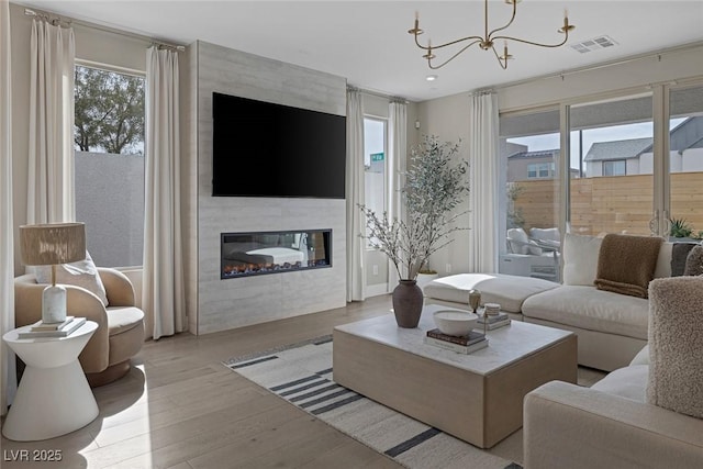 living area with wood finished floors, a chandelier, a large fireplace, and recessed lighting