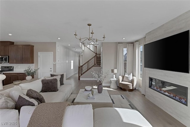 living room featuring light wood-style floors, a chandelier, stairway, recessed lighting, and baseboards