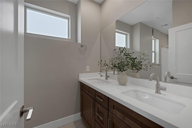 bathroom with double vanity and baseboards