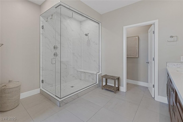 bathroom featuring a marble finish shower, baseboards, and vanity
