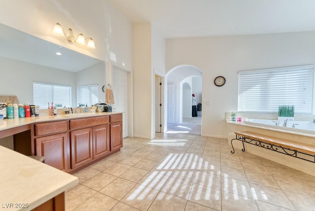 8137 Cape Flattery Ave, Las Vegas, NV 89147 - bathroom featuring tile patterned floors, vaulted ceiling, a garden tub, vanity, and baseboards
