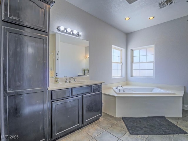 bathroom featuring a garden tub, vanity, tile patterned flooring, a textured ceiling, and recessed lighting