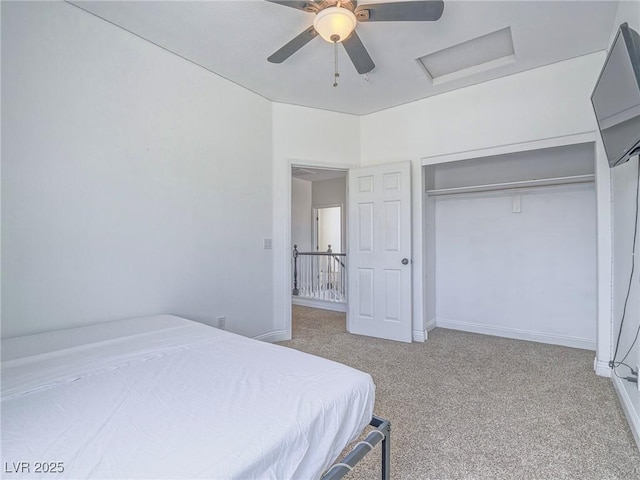carpeted bedroom with attic access, ceiling fan, a closet, and baseboards