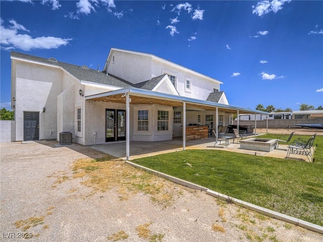 back of property with cooling unit, a patio, stucco siding, a yard, and a hot tub