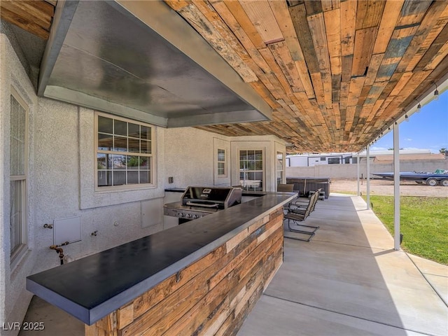 view of patio featuring an outdoor kitchen, area for grilling, and fence