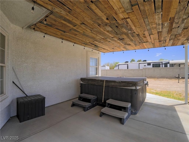 view of patio / terrace featuring a hot tub and fence