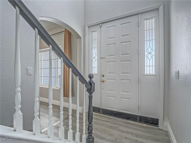 foyer entrance featuring a textured wall, stairway, healthy amount of natural light, and wood finished floors