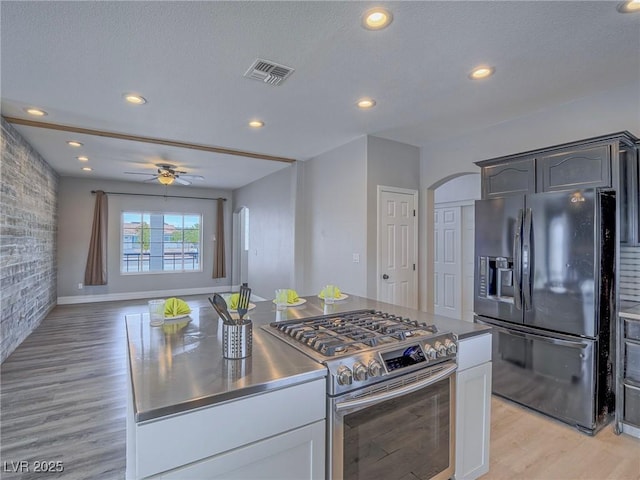 kitchen with black fridge, stainless steel range with gas stovetop, light wood-style flooring, ceiling fan, and recessed lighting