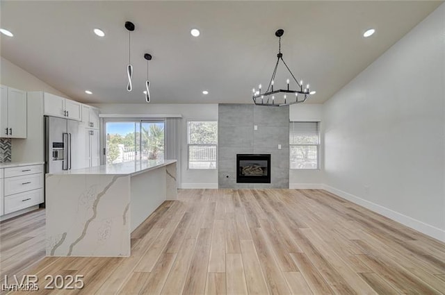 7460 Desert Flame Ct, Las Vegas, NV 89149 - unfurnished living room with light wood-type flooring, vaulted ceiling, recessed lighting, baseboards, and a tiled fireplace