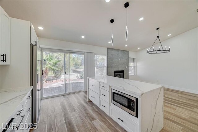 7460 Desert Flame Ct, Las Vegas, NV 89149 - kitchen featuring stainless steel appliances, light wood-style flooring, a tile fireplace, open floor plan, and recessed lighting