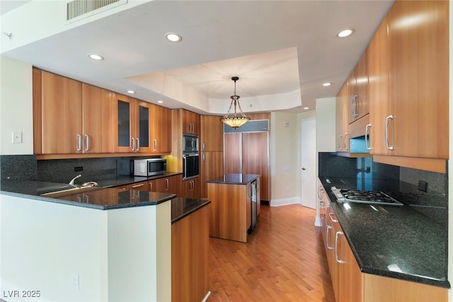 2857 Paradise Rd Unit 802, Las Vegas, NV 89109 - kitchen with stainless steel appliances, brown cabinetry, a tray ceiling, recessed lighting, and a kitchen island