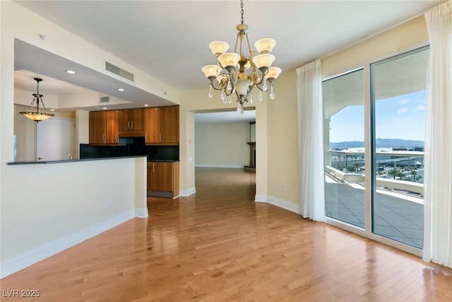 2857 Paradise Rd Unit 802, Las Vegas, NV 89109 - kitchen featuring brown cabinets, dark countertops, light wood finished floors, a chandelier, and baseboards