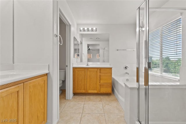bathroom featuring tile patterned floors, toilet, vanity, a bath, and a shower with door