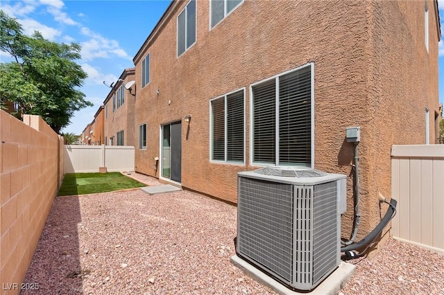 back of property featuring central AC unit, stucco siding, and a fenced backyard