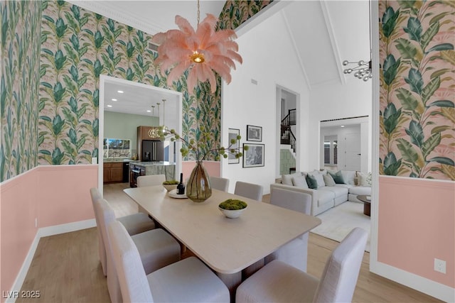 2160 Pueblo Cir, Las Vegas, NV 89169 - dining area featuring wallpapered walls, light wood-style floors, wainscoting, high vaulted ceiling, and baseboards