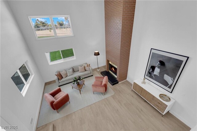 2160 Pueblo Cir, Las Vegas, NV 89169 - living area featuring wood finished floors, a towering ceiling, a lit fireplace, and baseboards