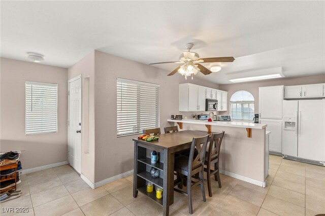 3125 N Buffalo Dr Unit 1103, Las Vegas, NV 89128 - kitchen with white refrigerator with ice dispenser, stainless steel microwave, a ceiling fan, a peninsula, and light countertops