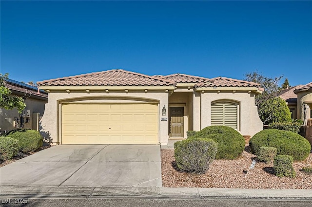 mediterranean / spanish-style home featuring concrete driveway, stucco siding, an attached garage, and a tiled roof
