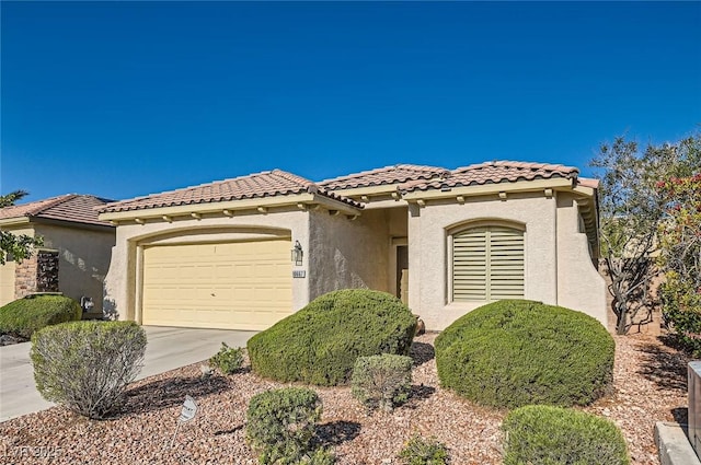 mediterranean / spanish house featuring an attached garage, stucco siding, concrete driveway, and a tile roof