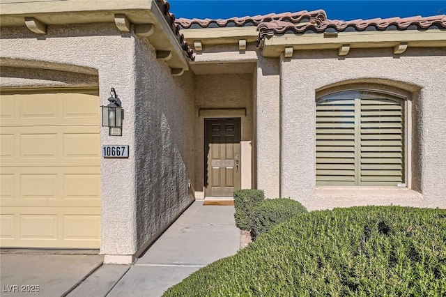 property entrance featuring stucco siding, a garage, and a tile roof
