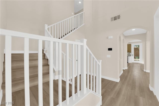 177 Rocky Star St, Henderson, NV 89012 - staircase featuring wood finished floors, arched walkways, a towering ceiling, baseboards, and recessed lighting